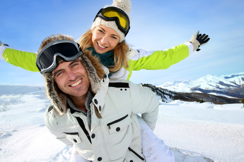 Cheerful snowboarder holding girlfriend on his back_shutterstock